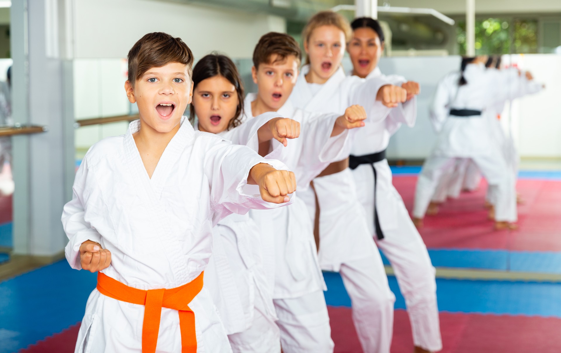 Team of motivated teenagers are engaged in karate in gym